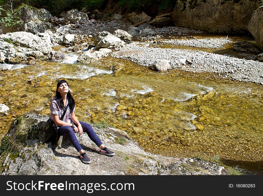 Woman sun bathing near a mountain river. Woman sun bathing near a mountain river