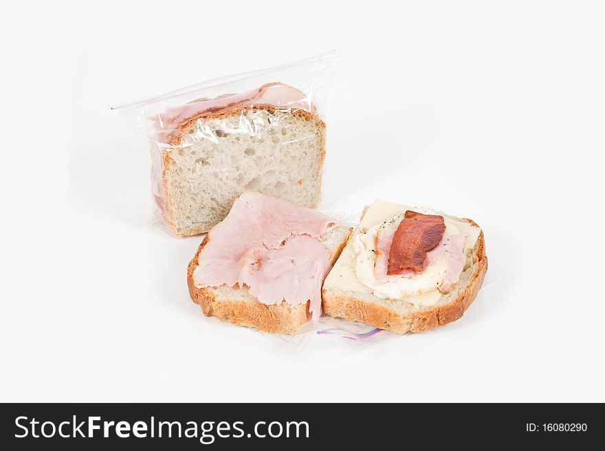 A studio angled shot of two homemade egg and cheese with ham and bacon sandwiches on a white background. A studio angled shot of two homemade egg and cheese with ham and bacon sandwiches on a white background.