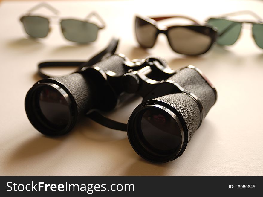 Binoculars and colored sunglasses on white background. Binoculars and colored sunglasses on white background