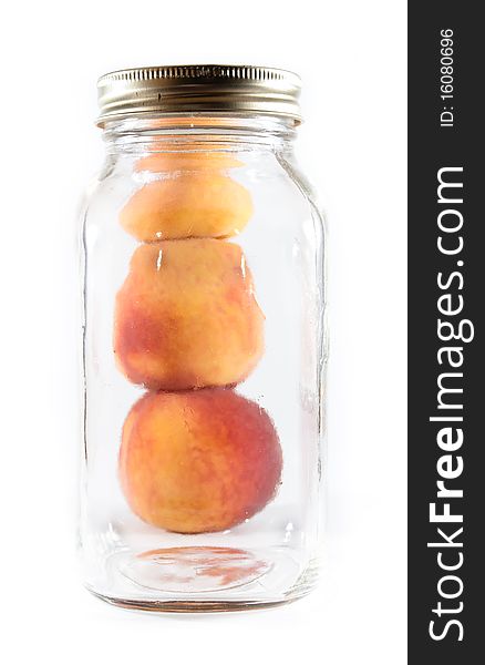 Three peaches pilled beside a glass preservative jar on a white isolated background. Three peaches pilled beside a glass preservative jar on a white isolated background.