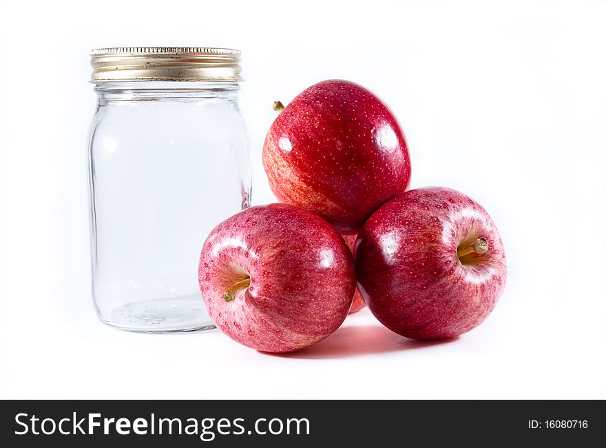 Three gala apples beside a mason canning jar