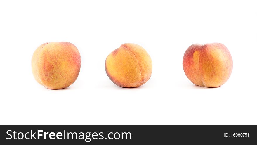 Three fresh fuzzy yellow and orange peaches lined in a row on a white isolated background. Three fresh fuzzy yellow and orange peaches lined in a row on a white isolated background