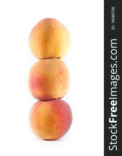 Three fresh fuzzy yellow and orange peaches stacked on each other on a white isolated background. Three fresh fuzzy yellow and orange peaches stacked on each other on a white isolated background.