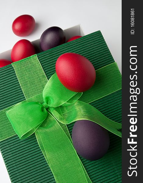 Many Easter eggs of different colours and a green gift box.