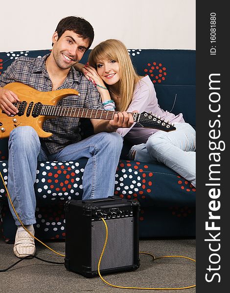 Romantic young couple resting on a sofa with a music