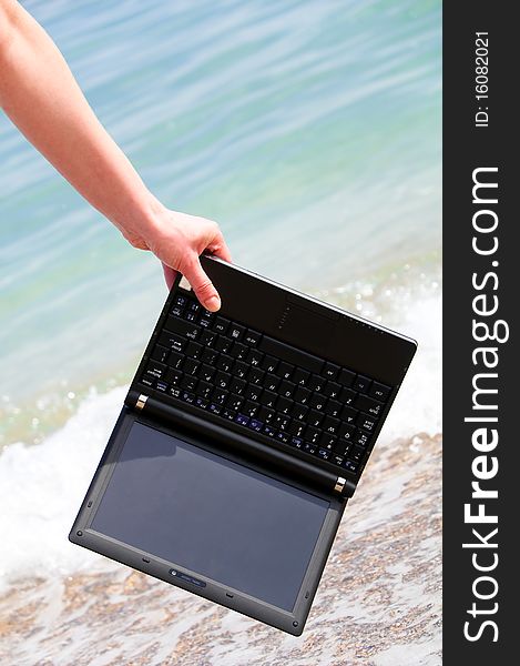 Handle a net book above the seawater waves. Pick up the technology out of the water concept. Concept of Internet addiction. Handle a net book above the seawater waves. Pick up the technology out of the water concept. Concept of Internet addiction.