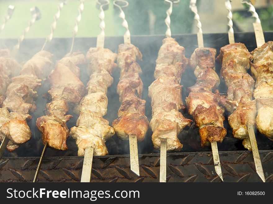 Meat is fried on skewers and a brazier there is a smoke. Meat is fried on skewers and a brazier there is a smoke