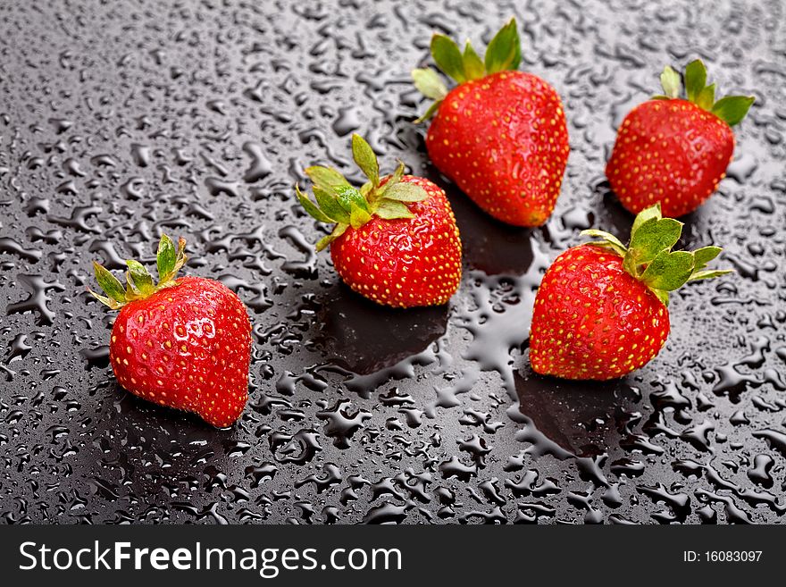 Strawberries on wet black background