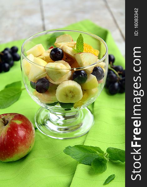 Fruit salad in a glass bowl on a green cloth