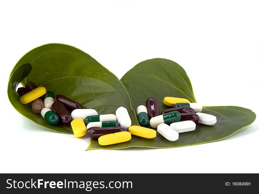 Pills in green leaf on white background