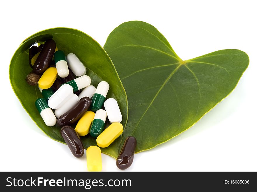 Pills in green leaf on white background
