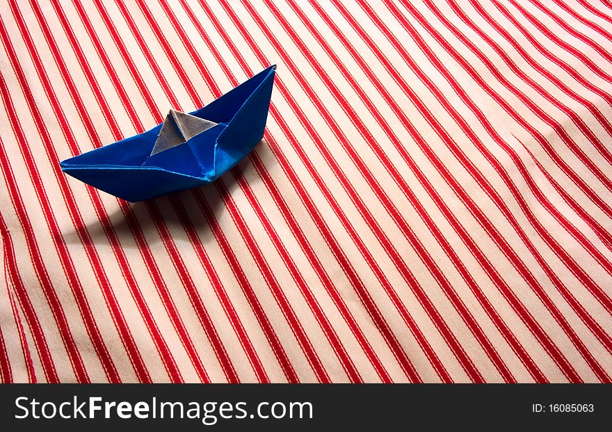 Blue paper boat on striped material