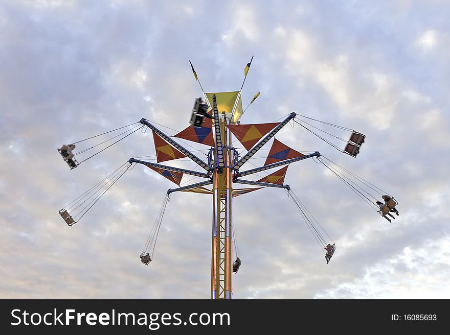 A tower county fair swing ride against a colorful evening sky, the motion creating a slight blur to the passengers. A tower county fair swing ride against a colorful evening sky, the motion creating a slight blur to the passengers