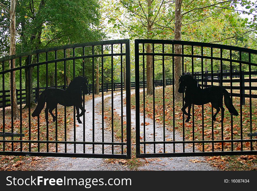 Closed iron gates with silhouettes of horses, barring entrance to a ranch. Closed iron gates with silhouettes of horses, barring entrance to a ranch