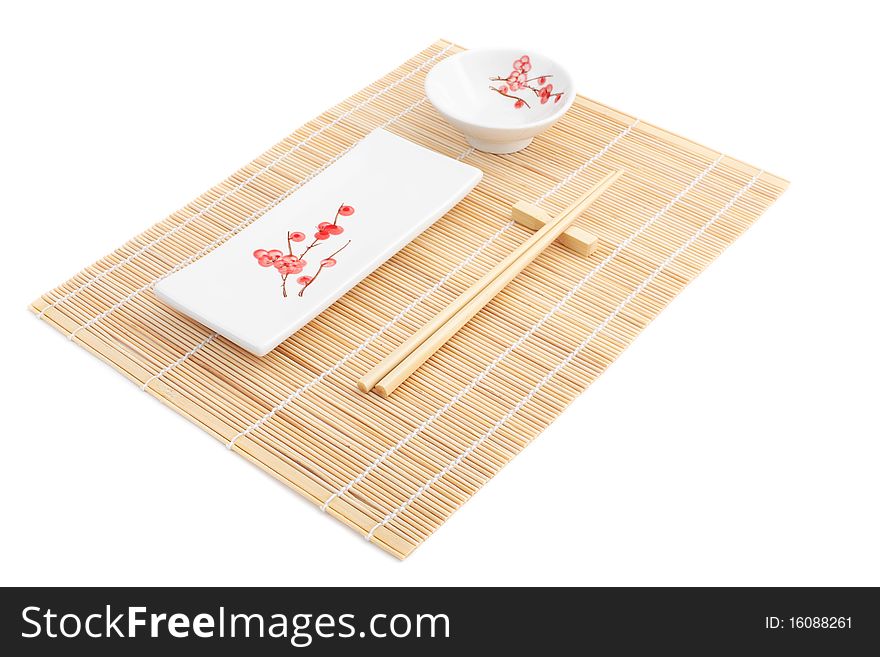 Sushi plates and chopsticks on bamboo mat