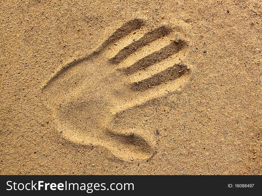 Print of a human hand on sand