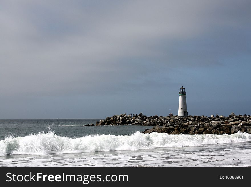 Lighthouse and sea waves crashing on rocks