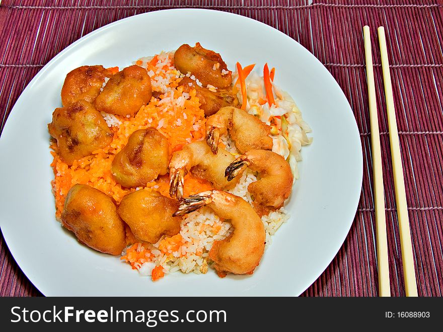 Plate of sweet and sour pork and shrimp on fried rice on purple bamboo place mat with chopsticks white plate. Plate of sweet and sour pork and shrimp on fried rice on purple bamboo place mat with chopsticks white plate