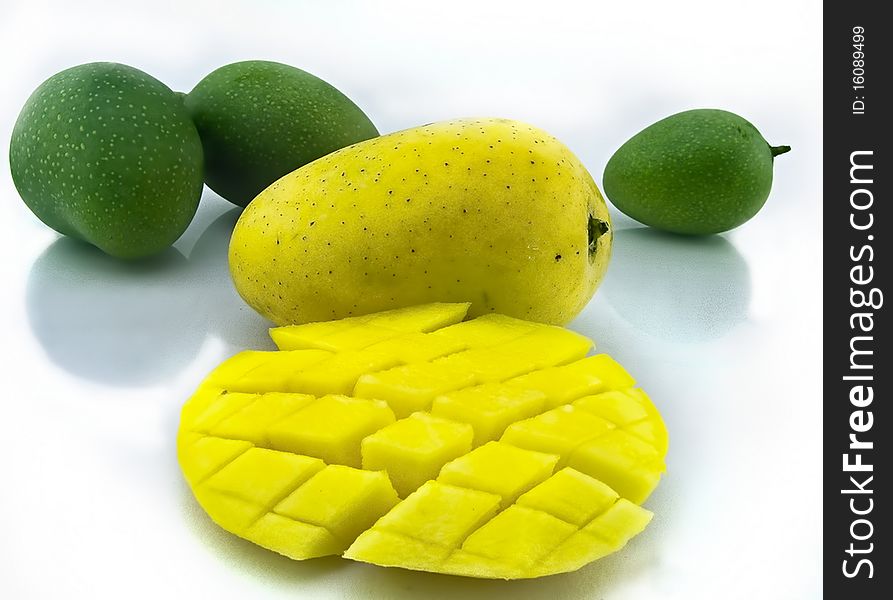 Mango with section along with unripe mango on white