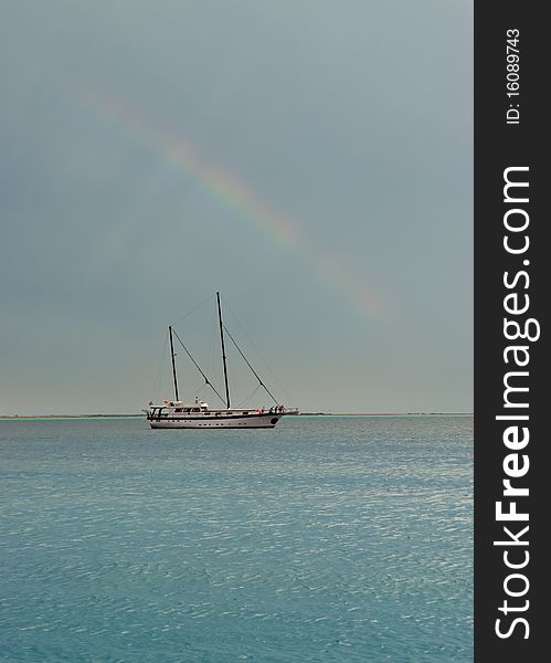 Rainbow with sailing boat on a flat sea