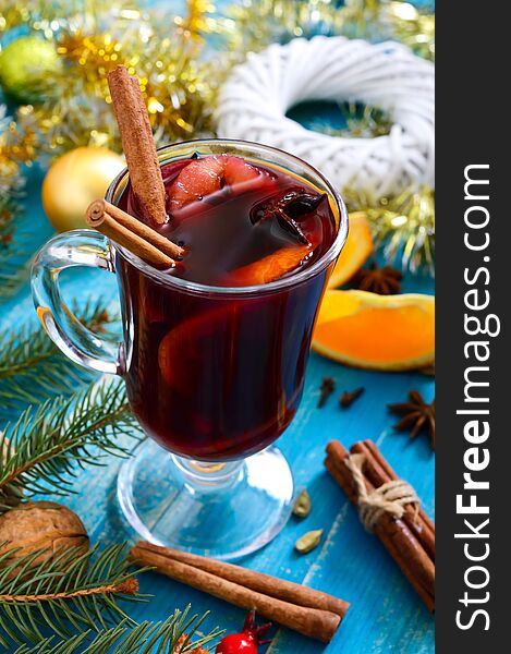 Christmas mulled red wine with spices and fruits on a blue wooden rustic table. Traditional hot drink with cinnamon, cardamom