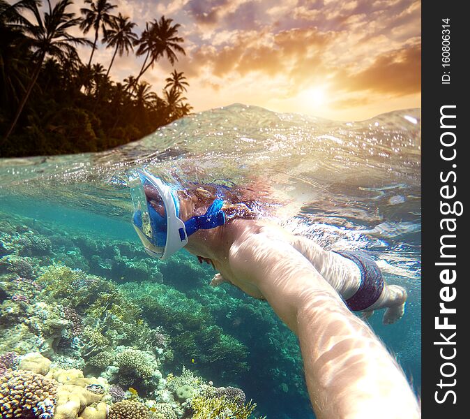 Snorkeling near a tropical island. Young man swims in the water. Sea vacation.