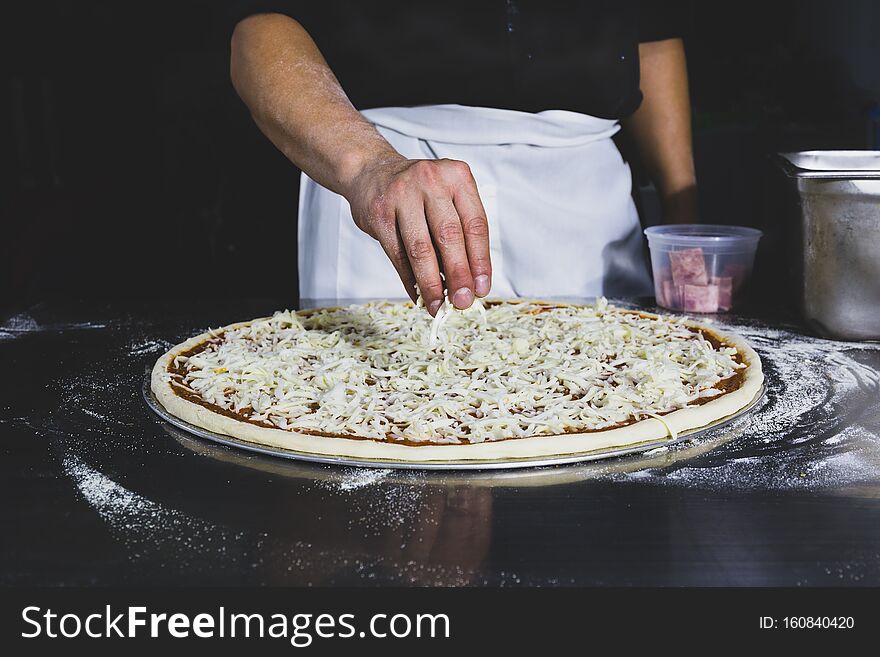 Chefs Hand Putting Cheese On The Pizza In Black Background.