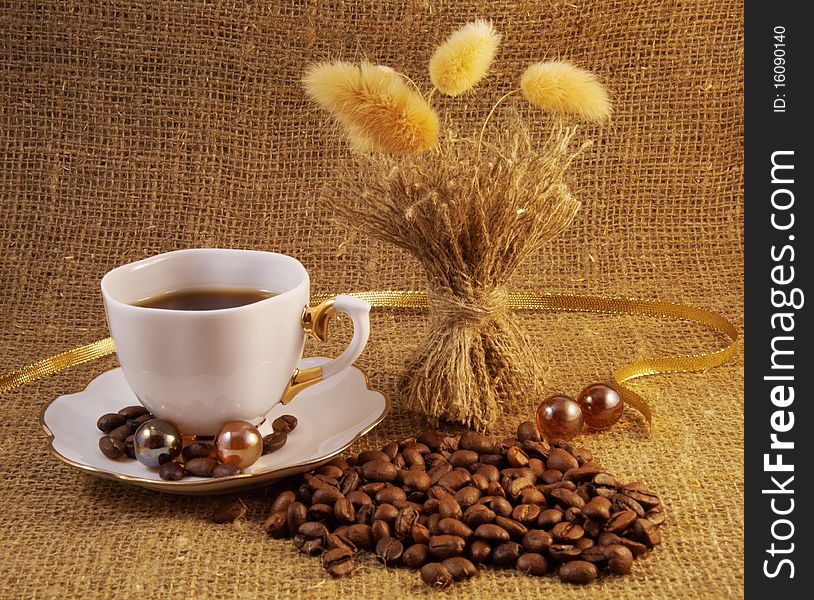 Coffee cup and coffee beans over burlap background
