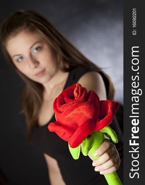 Beautiful girl giving/holding a huge plush rose isolated on black. Beautiful girl giving/holding a huge plush rose isolated on black