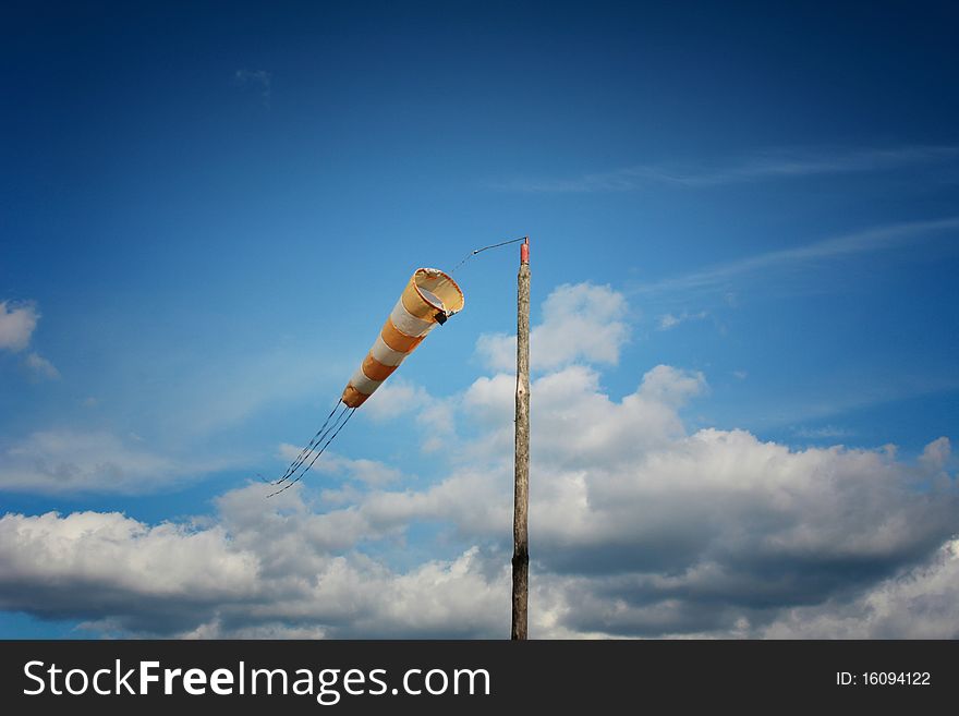 Windsock in front of clouds and dark blue sky. Windsock in front of clouds and dark blue sky.