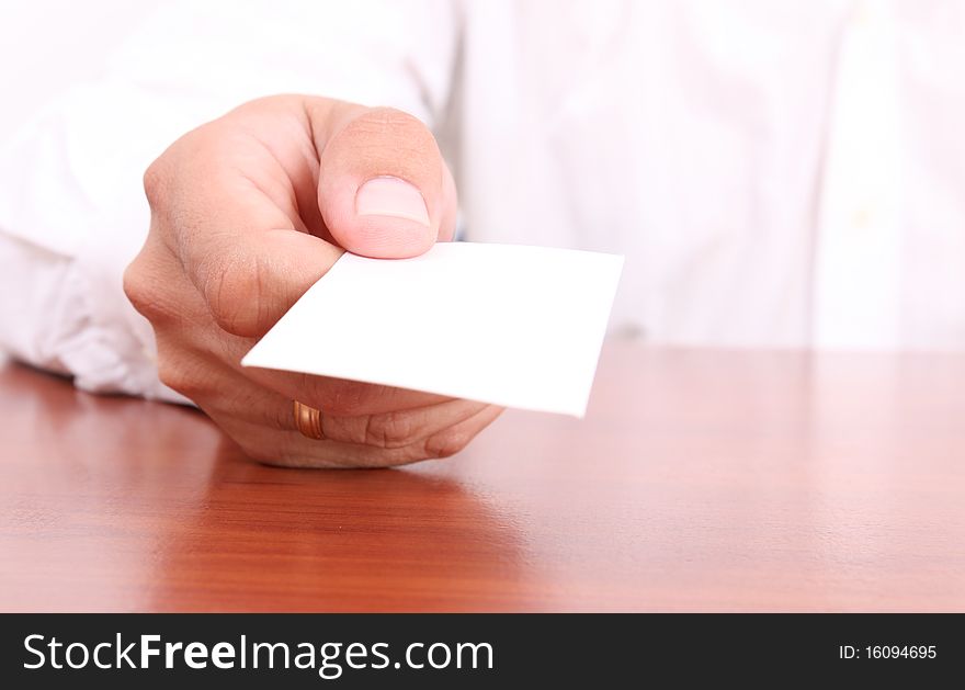 Hand giving a blank business card on wooden desk