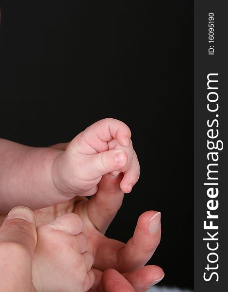 Hands of caucasian mother and baby, baby holding mother's finger