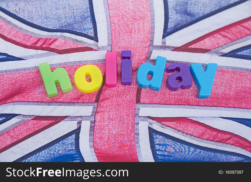 An image of the word holiday in colorful lower case letters placed on a blowing Union Jack flag. An image of the word holiday in colorful lower case letters placed on a blowing Union Jack flag.