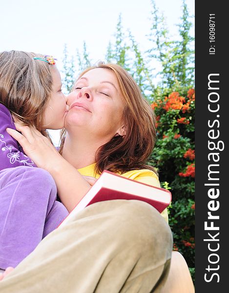 Kiss mother and daughter in the yard. Kiss mother and daughter in the yard