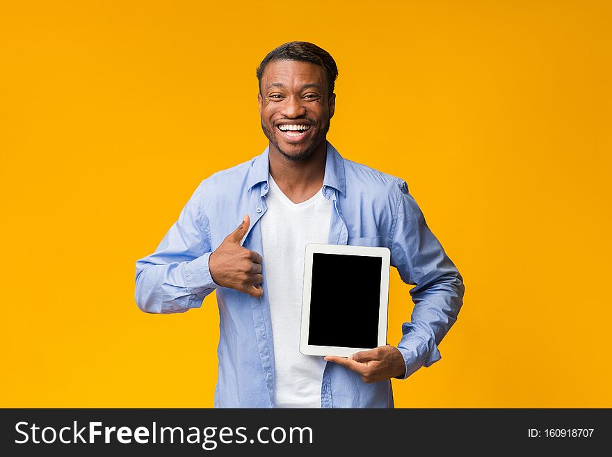 Cool App. Happy African American Man Showing Blank Tablet Screen Gesturing Thumbs Up Standing On Yellow Background. Studio Shot, Mockup. Cool App. Happy African American Man Showing Blank Tablet Screen Gesturing Thumbs Up Standing On Yellow Background. Studio Shot, Mockup