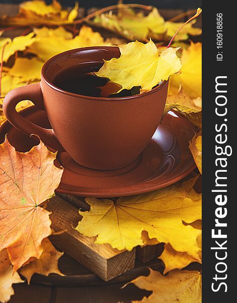 Autumn, fall leaves, hot cup of coffee on wooden table background