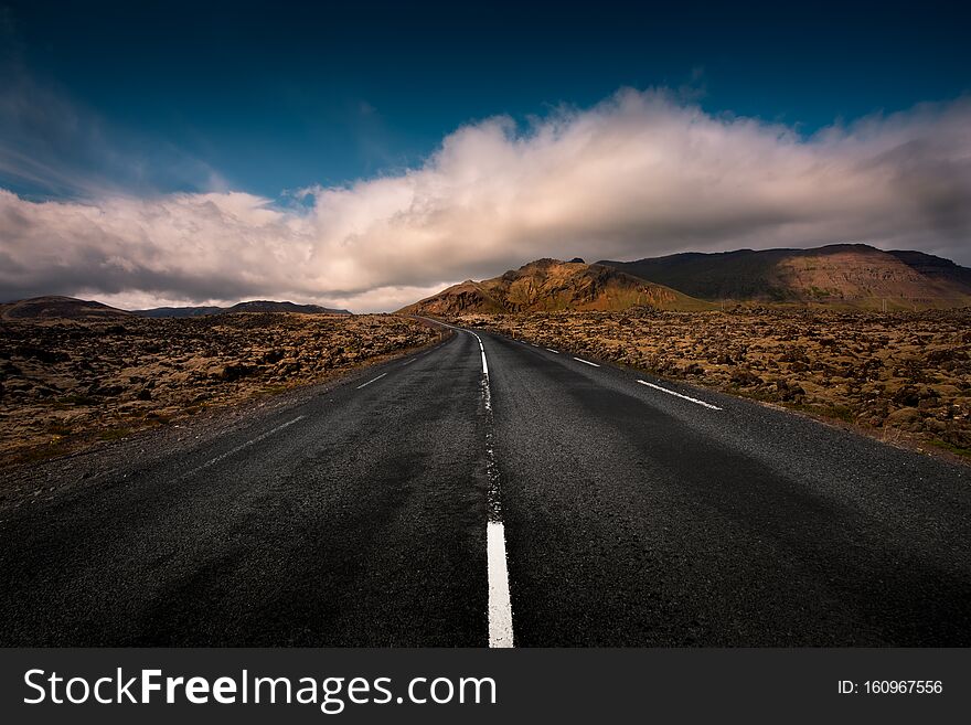 An empty Icelandic road leads through a mountain range. .Iceland