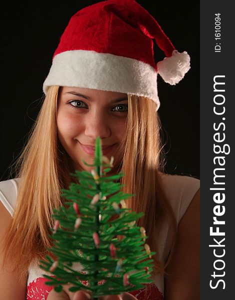 Christmas blonde girl offer a little Christmas-tree, black background. Christmas blonde girl offer a little Christmas-tree, black background