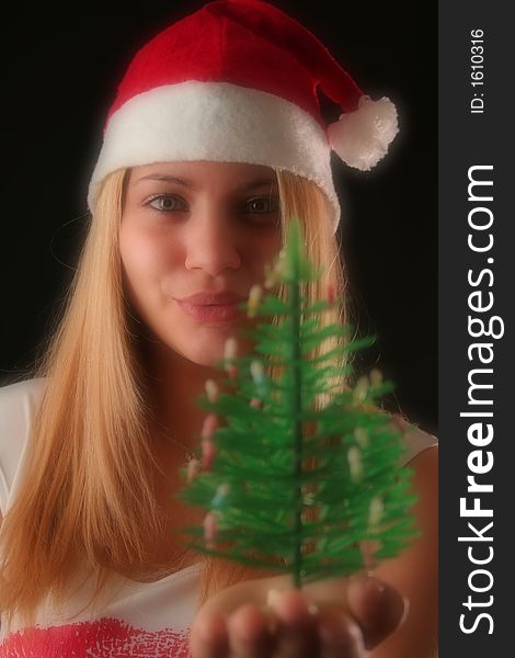 Christmas blonde girl offer a little Christmas-tree, black background. Christmas blonde girl offer a little Christmas-tree, black background