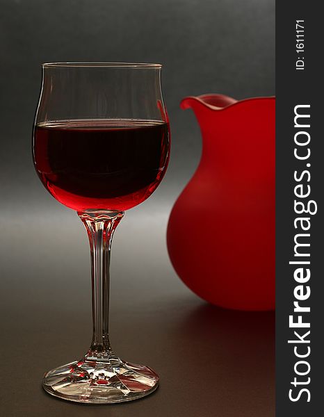 Glass of red wine with red vase in the background. Glass of red wine with red vase in the background