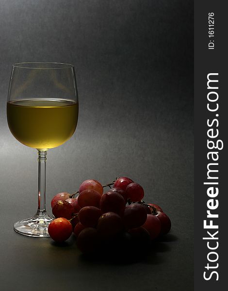 Low key image of chilled white wine with grapes on dark background