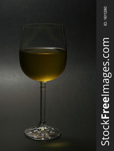Glass of chilled white wine against dark background. Glass of chilled white wine against dark background