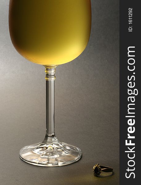 Low key image of chilled white wine with a ring placed at the bottom against dark background. Low key image of chilled white wine with a ring placed at the bottom against dark background