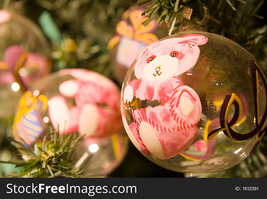 A buch of christmas balls on the tree with pink little bear