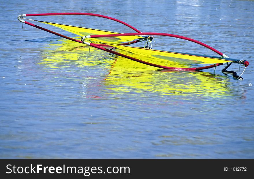 Two yellow and red sailboards on the water near a beach. Two yellow and red sailboards on the water near a beach