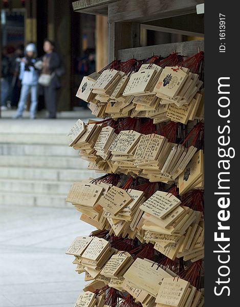 Shinto Prayer Boards at the Meji Temple, Tokyo, Japan.  There are poeple visible in the blurred background