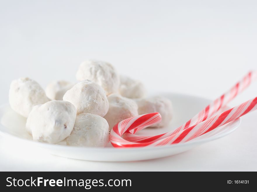 Two candy canes and round wedding cake cookies on a plate. Two candy canes and round wedding cake cookies on a plate.