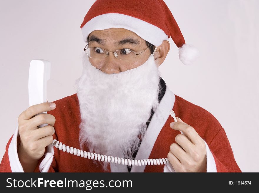 Asian Santa Claus holding a telephone receiver with expression. Asian Santa Claus holding a telephone receiver with expression.