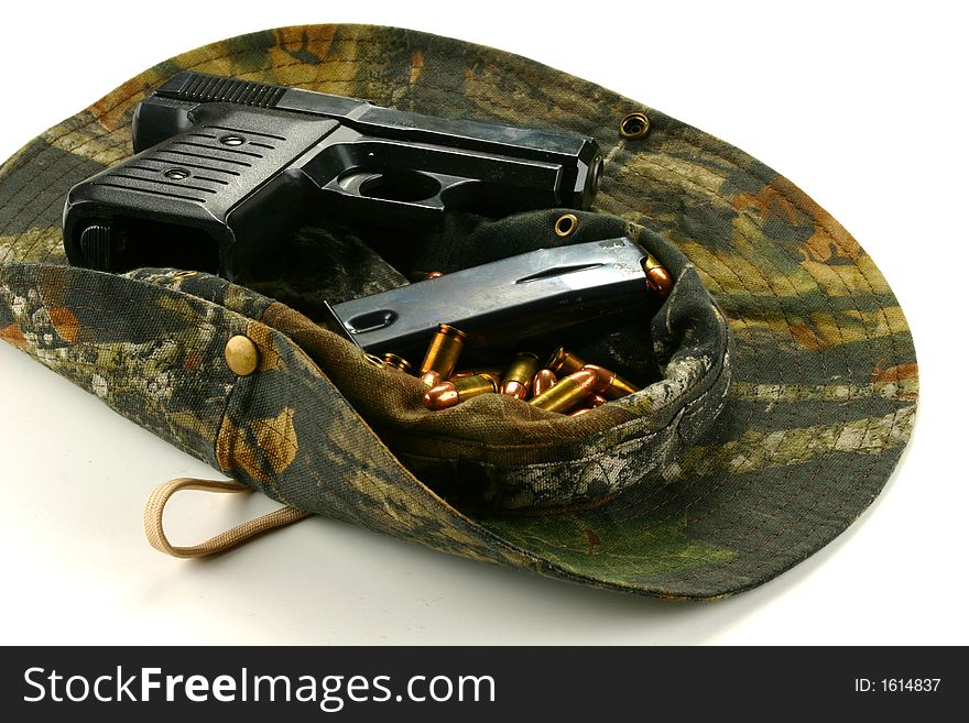 Handgun and ammo with a clip rest upon a hat. Handgun and ammo with a clip rest upon a hat