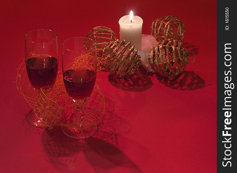 Romantic composition with wicker Christmas tree balls, candle and two glass of red wine (on red background with their shadows). Make specially some dark. Romantic composition with wicker Christmas tree balls, candle and two glass of red wine (on red background with their shadows). Make specially some dark.